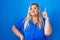 Caucasian plus size woman standing over blue background pointing finger up with successful idea