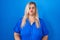 Caucasian plus size woman standing over blue background puffing cheeks with funny face