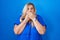 Caucasian plus size woman standing over blue background shocked covering mouth with hands for mistake