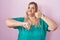 Caucasian plus size woman standing over pink background doing thumbs up and down, disagreement and agreement expression