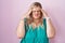 Caucasian plus size woman standing over pink background with hand on head, headache because stress