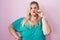 Caucasian plus size woman standing over pink background mouth and lips shut as zip with fingers