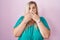 Caucasian plus size woman standing over pink background shocked covering mouth with hands for mistake