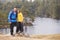 Caucasian pre-teen girl standing with her father on a rock by a lake, smiling to camera, lakeside background