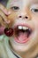 Caucasian preschool boy holding a ripe delicious cherry near his mouth. The child smiles and is ready to eat a sweet berry. Vitami
