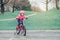 Caucasian preschooler girl riding pink bike bicycle in helmet on backyard road outside on spring summer day.