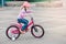 Caucasian preschooler girl riding pink bike bicycle in helmet on backyard road outside on spring summer day.