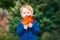 Caucasian red-haired boy with blue eyes holding autumn fall leaves in park