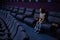 Caucasian red-haired woman sits on the last row in a cinema in an empty hall. The girl is watching a movie alone.