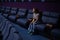 Caucasian red-haired woman sits on the last row in a cinema in an empty hall. The girl is watching a movie alone.