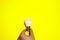 Caucasian\\\'s hand hold white eco lamp bulb isolated on yellow background. Business concept. Copy space place