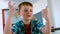 Caucasian schoolboy sitting at desk and counting with his finger in a classroom