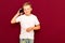 Caucasian schoolboy with touch phone on red background talking to a friend