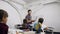 Caucasian schoolgirl raising hand and answering question of the korean teacher during a school lesson sitting behind the