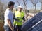 Caucasian seasoned technician talking to his young client beside the solar panels