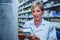 Caucasian senior female pharmacist checking labels on medication prescriptions standing in pharmacy drugstore