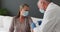 Caucasian senior male doctor wearing face mask giving covid-19 vaccine to woman at home