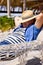 Caucasian senior man with hat on face and hands behind head sleeping on hammock at beach