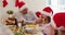 Caucasian senior man in santa hat wiping his daughter face with tissue sitting on dining table and e