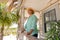 Caucasian senior man wearing hat smiling and contemplating while standing by railing in balcony