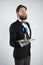 Caucasian servant with a beard in a formal business suit stands with a steel tray in his hand and a glass of wine on a white solid