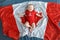 Caucasian smiling baby boy girl with blue eyes lying on large Canadian flag with red maple leaf