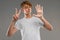 Caucasian smiling guy in a white T-shirt shows seven fingers on a gray studio background