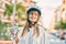 Caucasian sporty teenager girl wearing bike helmet and drinking bottle of water at the city