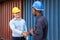 Caucasian supervisor hand shaking with African men worker while inspect the condition of all containers shipment, People and