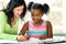 Caucasian teacher helping little african student at desk with sc