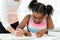 Caucasian teacher helping little black girl with maths.