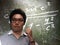 Caucasian teacher with his glasses use thump finger point to the blackboard