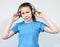 Caucasian teenage girl listening music with wireless headphones, blue t-shirt, a grey background