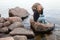 Caucasian teenage girl sitting on coastal stones