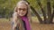 Caucasian teenage girl walking in the autumn park, turning back and looking at the camera. Cute teenager in glasses