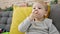 Caucasian toddler sitting on the sofa eating cookies at home