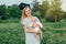 Caucasian Ukrainian blonde mother in blue dress holding newborn baby boy on summer day in park outside