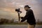 Caucasian videographer filming with cinema gimbal video dslr at sunset , professional video, video maker in event. Cinema lens on