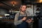 Caucasian waiter scrolling through online menu standing in trendy cafe preparing orders.
