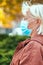 Caucasian woman 50 years old in a protective medical mask looks away in an autumn park. Safety in public place during