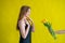 Caucasian woman accepts tulips as a gift on yellow background.