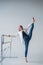 Caucasian woman in casual clothes pulls the longitudinal split at the ballet barre.