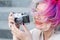 Caucasian woman with curly colored hair takes pictures on an old retro camera outdoors