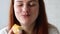 Caucasian woman eating a piece of taste doughnut with mango filling, enjoying. Hungry woman, close up