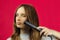 Caucasian woman, girl flattens her hair with a Curling iron