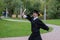 Caucasian woman in graduate gown dancing for joy outdoors.