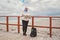 Caucasian woman in hat and jacket with backpack in winter sits on wooden pier on beach near North Sea. Denmark Copenhagen tourist