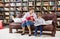 Caucasian woman holding baby daughter and sitting next to son on couch at home library