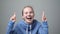 Caucasian woman holding fingers crossed shouting isolated on gray background