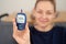 Caucasian woman holding glucose meter. Middle aged health. Hyperglycemia concept.